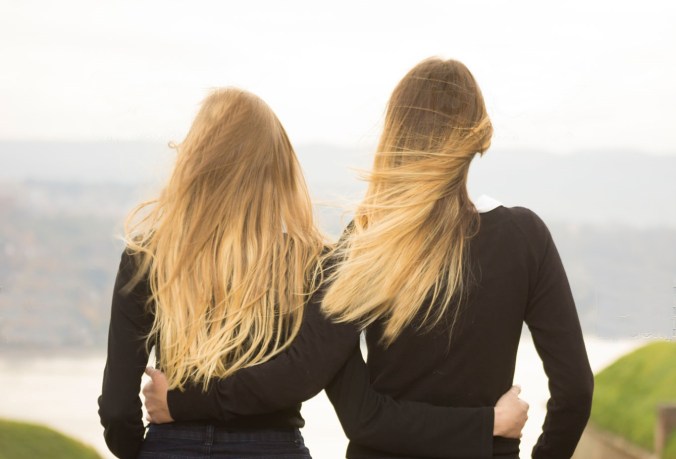Two identical teenage girlfriends, shot from back. Rear view